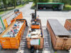 Sperrmüll-Container wird von einem mobilen Walzenverdichter bearbeitet